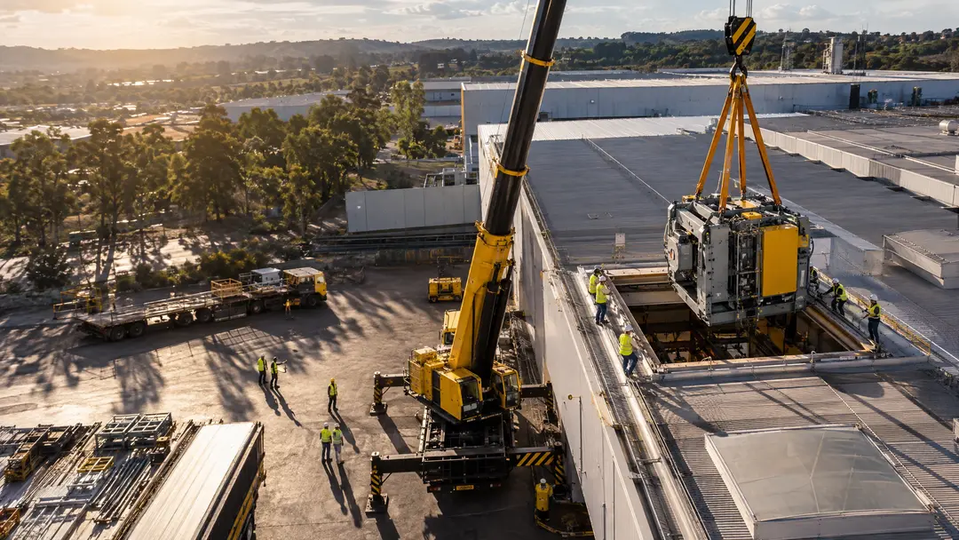 Máquina sendo descida por abertura em telhado industrial